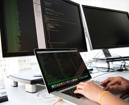 Person working on a laptop with several monitors