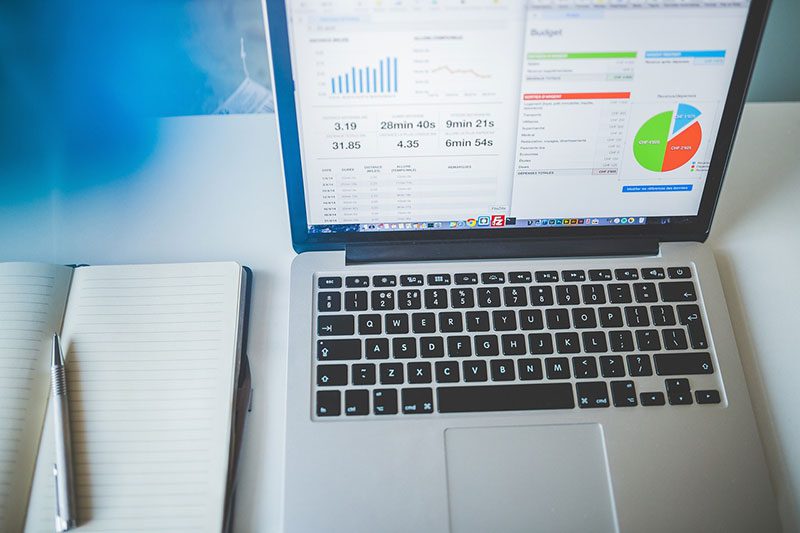 Notebook and laptop displaying database charts and graphs.