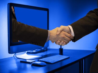 Handshake with one of the hands framed as coming from a computer monitor