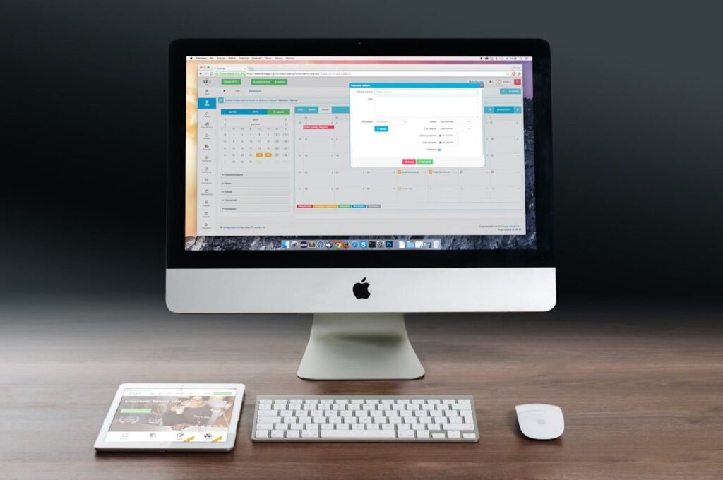 iMac, magic keyboard and mouse, and an iPad on a wooden table