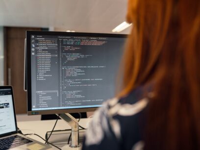 Person facing a computer screen that is displaying computer code.