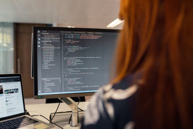 Person facing a computer screen that is displaying computer code.