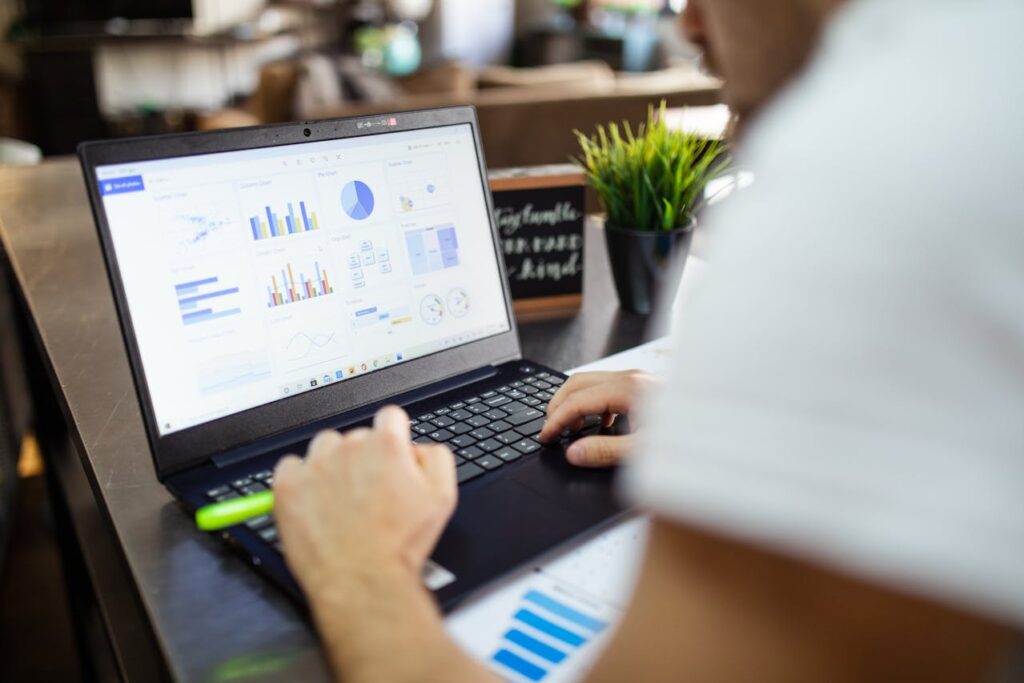 A person analyzes business intelligence data on a laptop displaying various charts and graphs